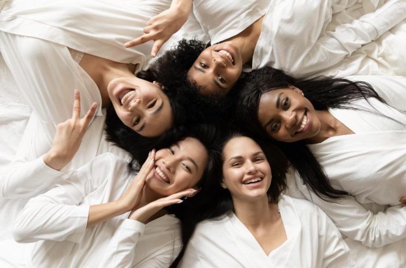 Five women in white robes representing wellness and beauty.