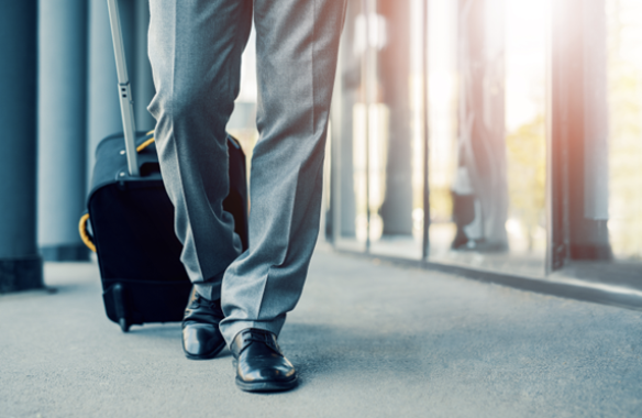 Business professional walking with a suitcase, reflecting a focus on travel and productivity, relevant to LavION's wellness solutions for energy and mental clarity.